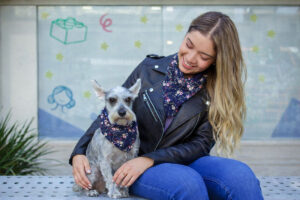 Woman and small dog wearing matching floral bandanas, showing their close bond