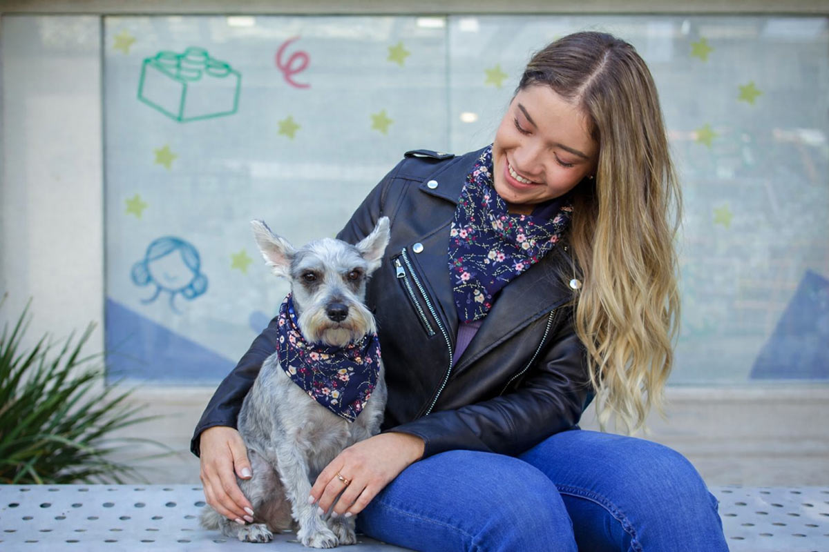 Woman and small dog wearing matching floral bandanas, showing their close bond